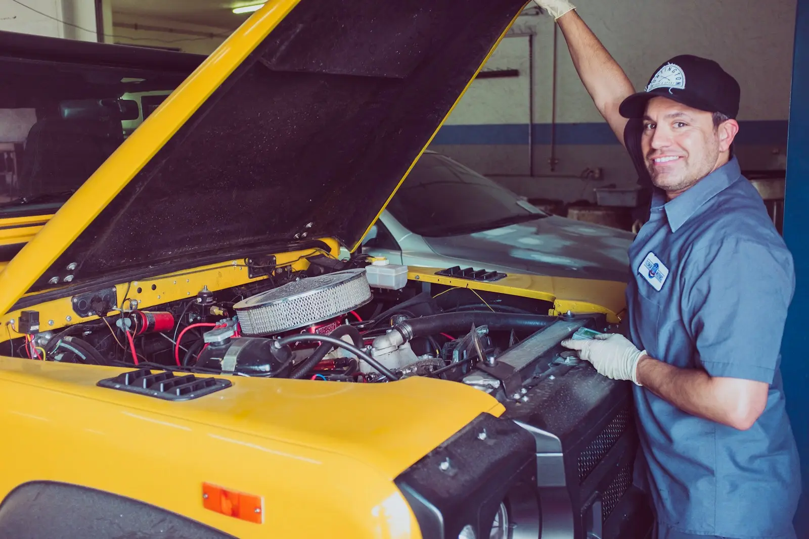 Dante Reyes leaning into the engine bay of a yellow sports car