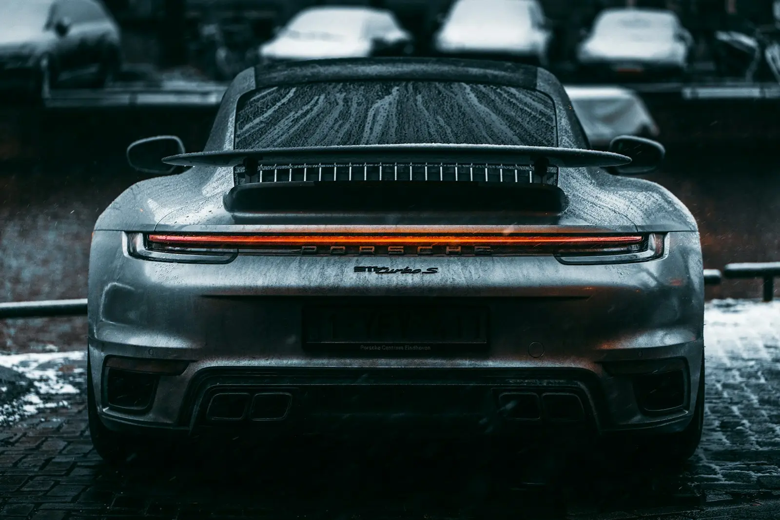 Rear three quarter of a grey Porsche 911 in the wet